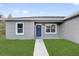 Close up view of a home's entry featuring a blue front door, windows, walkway, and manicured lawn at 42 Fisher Way Trak, Ocklawaha, FL 32179