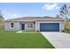 Charming single-story home showcasing a well-manicured lawn and a blue two-car garage, adding curb appeal at 42 Fisher Way Trak, Ocklawaha, FL 32179