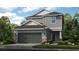 Two-story house with gray siding, dark gray garage door, and stone accents at 5702 Gingham Dr, Kissimmee, FL 34758