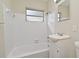 A bathroom with white tiled walls and shower, with a window providing natural light at 878 Rockhill St, Deltona, FL 32725