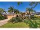 Charming brick home with lush landscaping, mature palm trees, and a well-maintained lawn under a clear blue sky at 402 Turnstone Way, Orlando, FL 32828