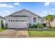 One-story house with a white exterior, two-car garage, and landscaped front yard at 104 Sunny Oak Trl, Kissimmee, FL 34746