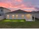 Inviting backyard showcasing the home's exterior, lush lawn, and serene sunset ambiance at 1207 Tank Trl, Haines City, FL 33844