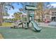 Community playground with slide, climbing structures, and picnic tables surrounded by lush green space and white picket fence at 13003 Plantation Park Cir # 1319, Orlando, FL 32821