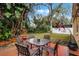 Outdoor seating area with a table and chairs nestled in lush greenery, with a peaceful backyard view at 13713 Meadowpark Ave, Orlando, FL 32826