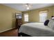 Comfortable bedroom featuring wood floors, a ceiling fan and a dresser with a television at 13713 Meadowpark Ave, Orlando, FL 32826