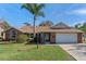 Charming brick home with a well-manicured lawn, palm tree and an attached two car garage at 1971 Urbana Ave, Deltona, FL 32725