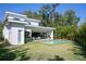 Rear exterior view of modern home with in-ground pool, covered patio and outdoor kitchen and surrounding landscaping at 2412 Chantilly Ave, Winter Park, FL 32789