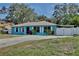 Charming ranch-style home with vibrant blue exterior, metal roof, stone accents, and large driveway at 27622 Lois Dr, Tavares, FL 32778