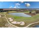 Scenic aerial view of the golf course featuring lush green fairways, a tranquil lake, and sand bunkers on a sunny day at 421 Boxwood Dr, Davenport, FL 33837