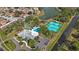 An aerial view reveals a community featuring a swimming pool, tennis courts, and a clubhouse nestled by a serene pond at 4817 Gallant Ln, Orlando, FL 32821