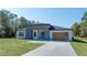 Modern home featuring clean lines, gray and white facade, complemented by a green lawn and blue skies at 5544 Sw 136Th Ave, Ocala, FL 34481