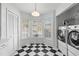 Bright laundry room features black and white tile, modern washer and dryer, and built-in shelving at 564 Shadow Glenn Pl, Winter Springs, FL 32708