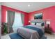 Bright bedroom features red walls, gray bedding, a bedside table and a picture hanging on the wall at 741 Gila Dr, Kissimmee, FL 34759