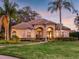 Beautiful luxury home with a tile roof, palm trees, manicured lawn, and elegant curb appeal at sunset at 8585 Cypress Ridge Ct, Sanford, FL 32771