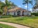 Beautiful single-story home with a well-manicured lawn, fountain, tile roof, and lush landscaping at 8585 Cypress Ridge Ct, Sanford, FL 32771