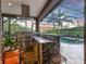 Outdoor kitchen featuring a stainless steel grill, granite countertops, and a stone bar overlooking the pool at 8585 Cypress Ridge Ct, Sanford, FL 32771