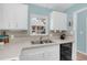 Well-lit kitchen with white cabinetry, tile countertops, and stainless steel sink beneath a window at 1220 Villa Ln # 135, Apopka, FL 32712