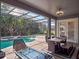 A covered patio overlooks the sparkling pool and spa in this home with a table, chairs, and a stylish modern fire pit at 16315 Bristol Lake Cir, Orlando, FL 32828