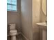 Powder room featuring a pedestal sink, toilet, and natural light from a window at 1820 Shumard Ave, St Cloud, FL 34771