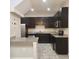 Well-lit kitchen featuring dark cabinets, granite countertops, stainless steel appliances, and tiled flooring at 1820 Shumard Ave, St Cloud, FL 34771