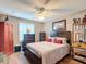 Relaxing bedroom with wooden floors, a ceiling fan, and a picture hanging over the bed at 2488 Cherokee Ct, The Villages, FL 32162