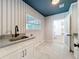 Bright laundry room features striped walls, tile floors, and modern white cabinets and sink at 2520 Chanute Trl, Maitland, FL 32751