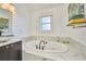 Elegant bathroom featuring a soaking tub with marble surround and a window for natural light at 441 Spoonbill Ct, Kenansville, FL 34739