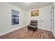 Bedroom with wood floors, a chair, painting, and a view into the dining area through the open window at 441 Spoonbill Ct, Kenansville, FL 34739