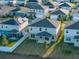 Aerial view of a residential neighborhood featuring two-story homes with solar panels, well-manicured lawns, and white fences at 613 Bloom Ter, Davenport, FL 33837