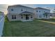 View of a backyard showing the covered patio, manicured lawn, and the rear exterior of the two story home at 613 Bloom Ter, Davenport, FL 33837