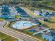 Aerial view showcasing a community pool with a splash pad, playground, cabana, and ample seating for residents' enjoyment at 613 Bloom Ter, Davenport, FL 33837