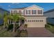 Two-story home featuring tan siding, red shutters, a brick driveway and an attached two-car garage at 613 Bloom Ter, Davenport, FL 33837