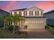 Two-story home featuring tan siding, red shutters, a brick driveway and an attached two-car garage at 613 Bloom Ter, Davenport, FL 33837