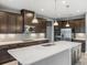 Stylish kitchen featuring dark cabinets, stainless steel appliances, and a white quartz island with pendant lights at 613 Bloom Ter, Davenport, FL 33837