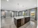 Kitchen island with stainless steel dishwasher, dark cabinets and white countertops overlooking a large living room area at 613 Bloom Ter, Davenport, FL 33837