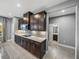 Well-lit kitchen with stainless steel appliances, dark cabinets and backsplash that leads into a half bathroom at 613 Bloom Ter, Davenport, FL 33837