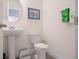 Charming half-bathroom with a pedestal sink, toilet, and framed artwork, offering a stylish and functional space at 739 Annabell Ridge Rd, Minneola, FL 34715