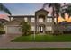Two-story home showcasing manicured lawn and lush tropical landscaping, complemented by a two car garage at 10068 Chardonnay Dr, Orlando, FL 32832