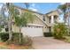 Two-story home showcasing manicured lawn and lush tropical landscaping, complemented by a two car garage at 10068 Chardonnay Dr, Orlando, FL 32832