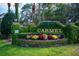 Community entrance sign with lush greenery, colorful flowers, and brick accents at 1150 Carmel Cir # 503, Casselberry, FL 32707
