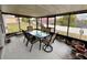 Screened sunroom with a glass top table, chairs, and potted plants overlooking the backyard at 11501 Pineloch Loop, Clermont, FL 34711