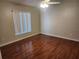 Bedroom with wood floors, ceiling fan, and a window with vertical blinds providing natural light at 11618 Kipling Ct, Clermont, FL 34711