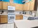Well-lit kitchen featuring light wood cabinets, white appliances, and decoratively accented with pops of color at 1217 Cypress Pointe Blvd, Davenport, FL 33896