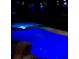 Night view of lit in-ground swimming pool and hot tub with dark background at 1217 Cypress Pointe Blvd, Davenport, FL 33896