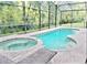 An inviting backyard pool and hot tub enclosed in a screened lanai, perfect for relaxation and outdoor enjoyment at 1217 Cypress Pointe Blvd, Davenport, FL 33896