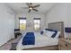 Cozy bedroom with neutral decor, ceiling fan, two windows and upholstered headboard at 15732 Shorebird Ln, Winter Garden, FL 34787