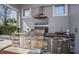 This outdoor kitchen has stone accents, a stainless steel grill, vent hood, sink and concrete counter at 15732 Shorebird Ln, Winter Garden, FL 34787