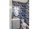 Stylish powder room featuring bold floral wallpaper, a gray vanity, and a modern oval mirror at 15732 Shorebird Ln, Winter Garden, FL 34787