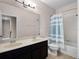 Well-lit bathroom featuring double sinks, large mirror, shower-tub combination, and a blue and white striped shower curtain at 15863 Citrus Grove Loop, Winter Garden, FL 34787